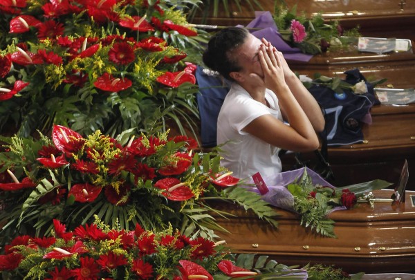 A woman cries next to coffins of victims of coach crash during funeral service at Monteruscello Palasport near Pozzuoli