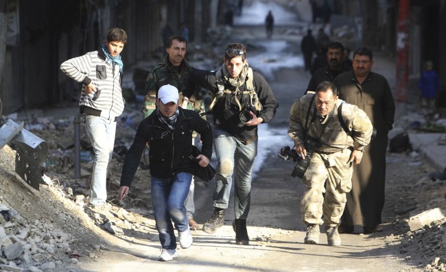 Journalists Karcha and Fujimoto run for cover next to an unidentified fixer in a street in Aleppo's district of Salaheddine