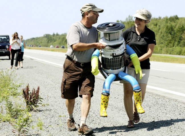 Anne Saulnier and her husband Brian carry the anthropomorphic robot named hitchBOT to their truck on Highway 102 outside of Halifax