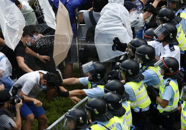 Riot police use pepper spray as they clash with protesters, as tens of thousands of protesters block the main street to the financial Central district outside the government headquarters in Hong Kong