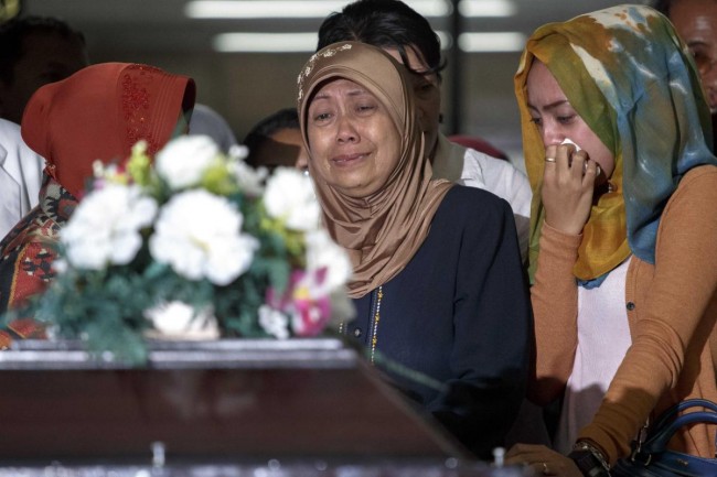 The mother and other family members of a passenger of Airasia QZ8501 cry upon receiving her remains at Bhayankara Hospital in Surabaya
