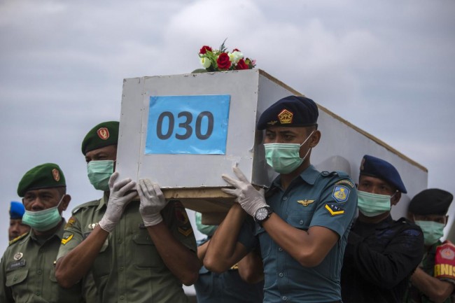 Indonesian military personnel carry a casket containing the remains of a passenger onboard AirAsia flight QZ8501, recovered off the coast of Borneo, at a military base in Surabaya