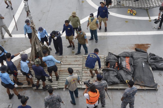 Indonesian Navy personnel lay recovered dead bodies from AirAsia flight QZ8501 on the the deck of the Indonesian Navy vessel KRI Banda Aceh, at sea