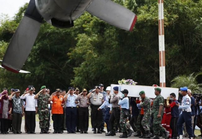 Caskets containing the remains of passengers from AirAsia QZ8501 are carried into an Indonesian military cargo plane to be transported  back to Surabaya, at the airport in Pangkalan Bun