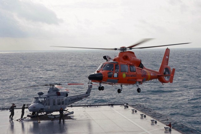 An Indonesian search and rescue helicopter prepares for landing during operations to lift the tail of AirAsia flight QZ8501 from the Java sea