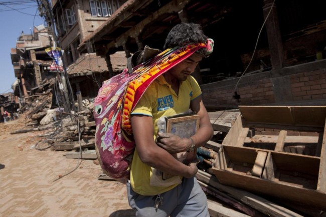 A Nepalese man carries his belongings from earthquake debris in Bhaktapur, on the outskirts of Kathmandu, Nepal, Monday, April 27, 2015. A strong magnitude earthquake shook Nepals capital and the densely populated Kathmandu valley on Saturday devastating the region and leaving tens of thousands shell-shocked and sleeping in streets. (AP Photo/Niranjan Shrestha)