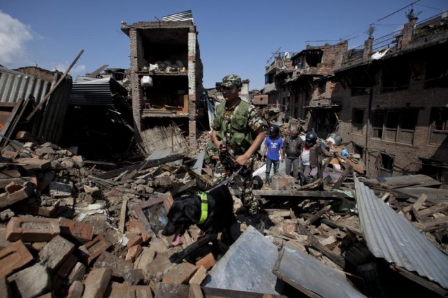 A rescue team with a sniffer dog walks at the site of destruction caused by Saturdays earthquake in Bhaktapur, on the outskirts of Kathmandu, Nepal, Monday, April 27, 2015. A strong magnitude earthquake shook Nepals capital and the densely populated Kathmandu valley on Saturday devastating the region and leaving tens of thousands shell-shocked and sleeping in streets. (AP Photo/Niranjan Shrestha)