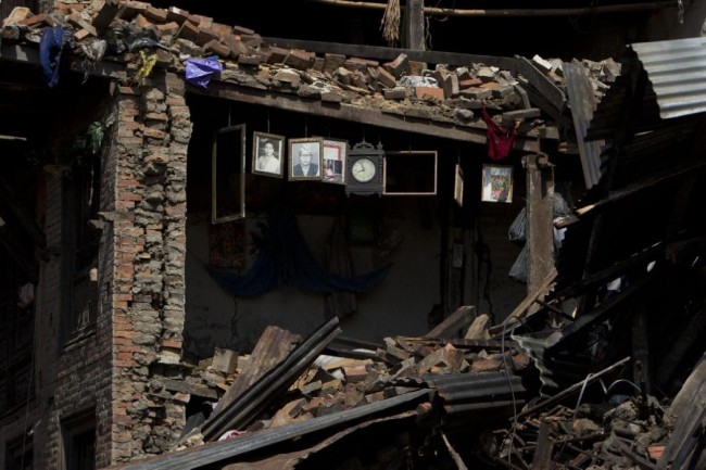 Portraits and a wall clock is seen hanging on the remains of a house damaged in Saturday's earthquake in Bhaktapur, on the outskirts of Kathmandu, Nepal, Monday, April 27, 2015. A strong magnitude earthquake shook Nepals capital and the densely populated Kathmandu valley on Saturday devastating the region and leaving tens of thousands shell-shocked and sleeping in streets. (AP Photo/Niranjan Shrestha)