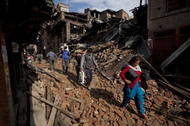Nepalese residents carry belongings from their destroyed homes as they walk through debris of Saturday's earthquake, in Bhaktapur on the outskirts of Kathmandu, Nepal, Monday, April 27, 2015. A strong magnitude earthquake shook Nepals capital and the densely populated Kathmandu valley on Saturday devastating the region and leaving tens of thousands shell-shocked and sleeping in streets. (AP Photo/Niranjan Shrestha)