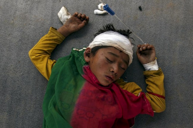 An injured boy sleeps on the ground outside the overcrowded Dhading hospital, in the aftermath of Saturday's earthquake, in Dhading Besi, Nepal April 27, 2015. REUTERS/Athit Perawongmetha       TPX IMAGES OF THE DAY