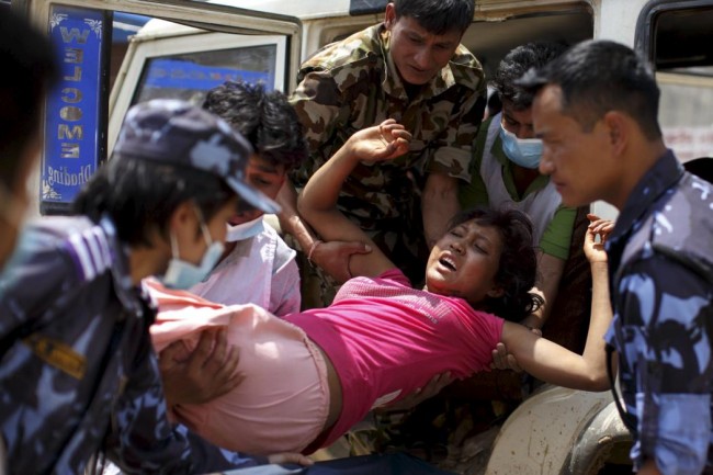 Military personnel and volunteers carry an injured woman into Dhading hospital, in the aftermath of Saturday's earthquake, in Dhading Besi, Nepal April 27, 2015.  REUTERS/Athit Perawongmetha
