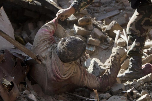 EDS NOTE GRAPHIC CONTENT - Members of Nepalese army rescue a dead body from inside a building that collapsed in Saturdays earthquake, in Bhaktapur, on the outskirts of Kathmandu, Nepal, Monday, April 27, 2015. A strong magnitude earthquake shook Nepals capital and the densely populated Kathmandu valley on Saturday devastating the region and leaving tens of thousands shell-shocked and sleeping in streets. (AP Photo/Niranjan Shrestha)