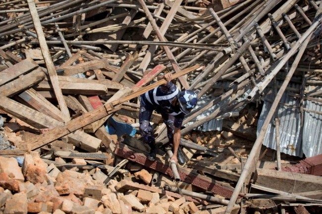A member of Nepalese police personnel tries to clear the rubble with his hands while looking for survivors at the compound of a collapsed temple, in the aftermath of Saturday's earthquake in Kathmandu, Nepal, April 27, 2015. REUTERS/Danish Siddiqui