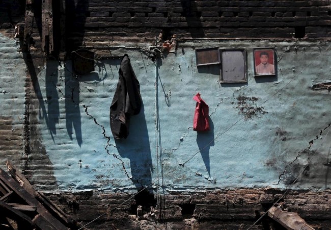 A coat and a framed portrait are seen hanging on a cracked wall of a damaged house after an earthquake in Bhaktapur, Nepal April 27, 2015. REUTERS/Adnan Abidi