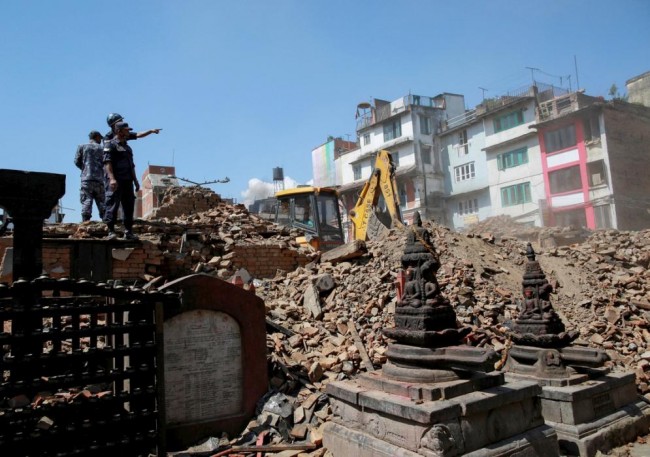 Nepalese police personnel look on as an excavator is used to dig through rubble to search for bodies following Saturday's earthquake in Kathmandu, Nepal, April 27, 2015. REUTERS/Danish Siddiqui