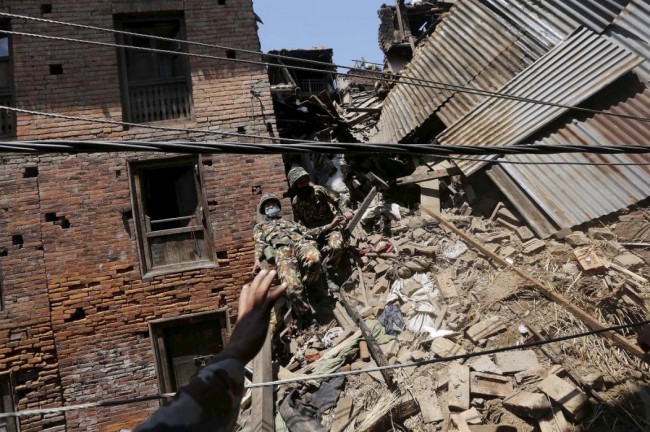 A Nepalese army soldier loses his balance while descending from a mound of rubble during the recovery of a body from a house, in the aftermath of Saturday's earthquake in Bhaktapur, Nepal April 27, 2015. REUTERS/Adnan Abidi