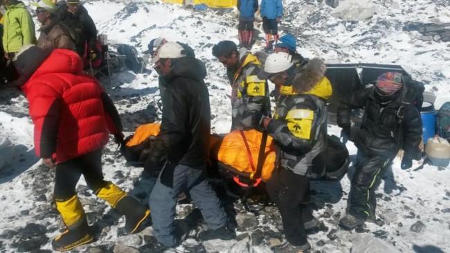 In this Sunday, April 26, 2015 photo, a person critically injured in an avalanche is carried on a stretcher to be evacuated out of Everest Base Camp, Nepal. An avalanche on Saturday, set off by the massive earthquake that struck Nepal, left more than a dozen people dead and dozens more injured. (AP Photo/Nima Namgyal Sherpa)