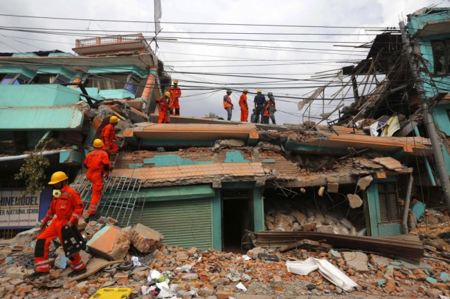 India's National Disaster Response Force personnel look for survivors in a building, in Kathmandu, Nepal, Sunday, April 26, 2015. Sleeping in the streets and shell-shocked, Nepalese cremated the dead and dug through rubble for the missing Sunday, a day after a massive Himalayan earthquake devastated the region and destroyed homes and infrastructure. (AP Photo/Manish Swarup)