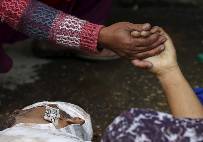 A woman holds the hand of a deceased relative who died during an earthquake outside a hospital in Kathmandu, Nepal April 26, 2015. Rescuers dug with their bare hands and bodies piled up in Nepal on Sunday after the earthquake devastated the heavily crowded Kathmandu Valley, killing more than 2,200 people, and triggered a deadly avalanche on Mount Everest. (REUTERS/Adnan Abidi)