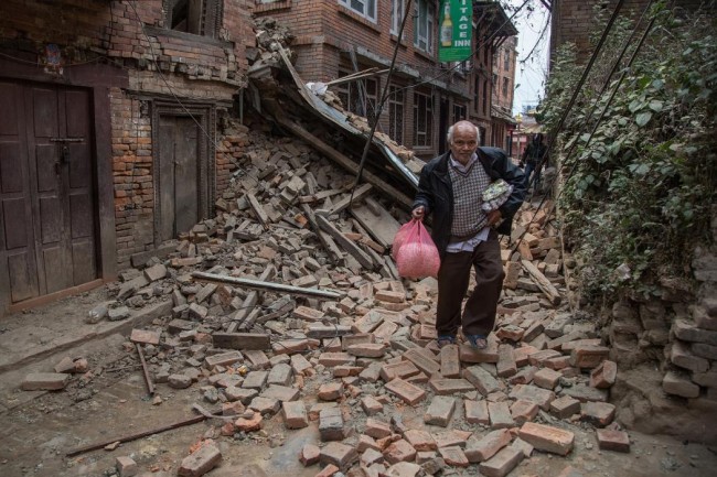 A man runs down a street covered in debris after buildings collapsed on April 26, 2015 in Bhaktapur, Nepal. (Omar Havana/Getty Images)