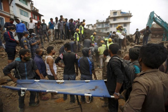 Rescue workers search for bodies as a stretcher is kept ready after an earthquake hit, in Kathmandu, Nepal April 25, 2015. The powerful earthquake struck Nepal and sent tremors through northern India on Saturday, killing hundreds of people, toppling an historic 19th-century tower in the capital Kathmandu and touching off a deadly avalanche on Mount Everest. (REUTERS/Navesh Chitrakar)
