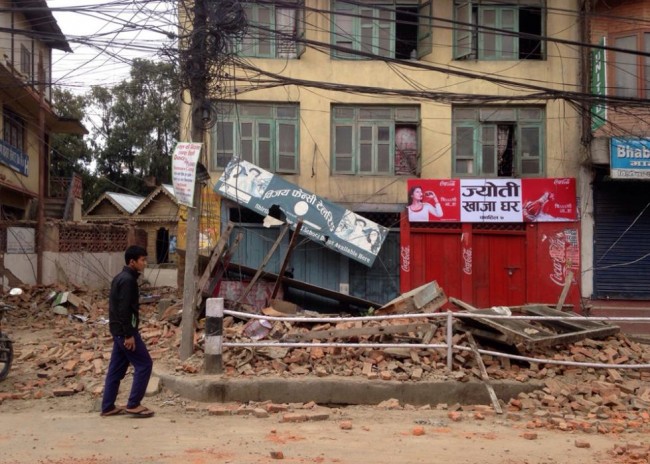 An  man walks past damage caused by an earthquake in Kathmandu, Nepal, Saturday, April 25, 2015. A strong magnitude-7.9 earthquake shook Nepal's capital and the densely populated Kathmandu Valley before noon Saturday, causing extensive damage with toppled walls and collapsed buildings, officials said. (AP Photo/ Niranjan Shrestha)