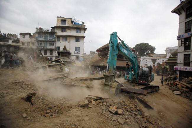 A crane removes debris from the site of a building that collapsed in an earthquake in Kathmandu, Nepal, Saturday, April 25, 2015. A strong magnitude-7.9 earthquake shook Nepal's capital and the densely populated Kathmandu Valley before noon Saturday, causing extensive damage with toppled walls and collapsed buildings, officials said. (AP Photo/ Niranjan Shrestha)