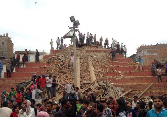 People stand around damage caused by an earthquake at Durbar Square in Kathmandu, Nepal, Saturday, April 25, 2015. A strong magnitude-7.9 earthquake shook Nepal's capital and the densely populated Kathmandu Valley before noon Saturday, causing extensive damage with toppled walls and collapsed buildings, officials said. (AP Photo/ Niranjan Shrestha)