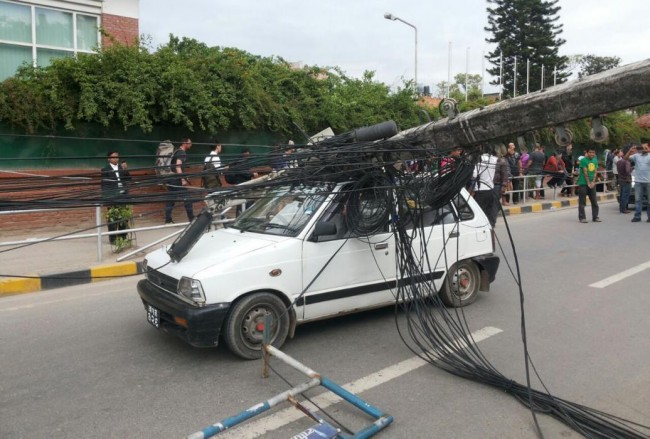 A car stands under the weight of an electric pole after it collapsed following an earthquake in Kathmandu, Nepal, Saturday, April 25, 2015. A strong magnitude-7.9 earthquake shook Nepal's capital and the densely populated Kathmandu Valley before noon Saturday, causing extensive damage with toppled walls and collapsed buildings, officials said. A magnitude-6.6 aftershock hit about an hour later, and smaller aftershocks continued to ripple through the region for hours. (AP Photo/Tashi Sherpa)
