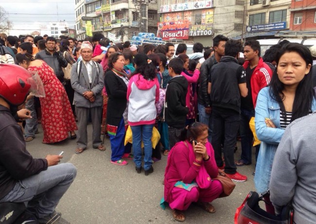 A group of people gather outdoors on a street as an earthquake hits Kathmandu city, Nepal, Saturday, April 25, 2015. A strong magnitude-7.9 earthquake shook Nepal's capital and the densely populated Kathmandu Valley before noon Saturday, causing extensive damage with toppled walls and collapsed buildings, officials said. (AP Photo/ Niranjan Shrestha)