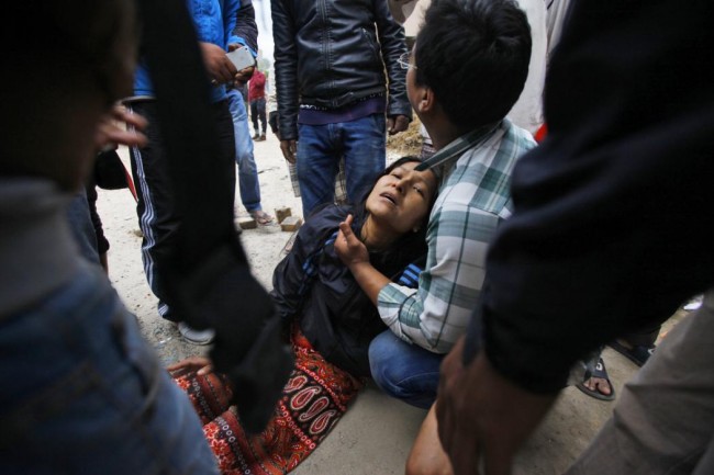 A woman cries as her son remains trapped in the debris of a building that collapsed in an earthquake in Kathmandu, Nepal, Saturday, April 25, 2015. A strong magnitude-7.9 earthquake shook Nepal's capital and the densely populated Kathmandu Valley before noon Saturday, causing extensive damage with toppled walls and collapsed buildings, officials said. (AP Photo/ Niranjan Shrestha)