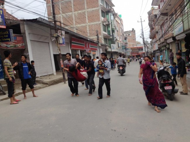 In this photo provided by Guna Raj Luitel, an injured woman is carried just after an earthquake in Kathmandu, Nepal, Saturday, April 25, 2015. A powerful earthquake shook Nepal's capital and the densely populated Kathmandu Valley before noon Saturday, collapsing houses, leveling centuries-old temples and cutting open roads in the worst temblor in the Himalayan nation in over 80 years. (Guna Raj Luitel via AP)