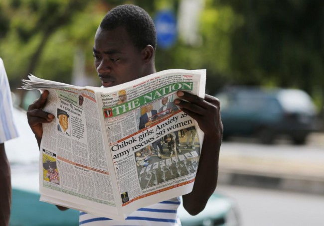 A man is seen reading a newspaper featuring a front page article about a group of women being rescued by the Nigerian army, in Abuja, Nigeria April 29, 2015. More than 200 schoolgirls abducted from their school dormitories by Boko Haram militants last year are not among the nearly 300 girls and women rescued in an army operation on Tuesday, an army spokesman said. Nigeria's army said it had rescued 200 girls and 93 women on Tuesday during a military operation to wrest back the Sambisa Forest in the northeast from the militant group. REUTERS/Afolabi Sotunde