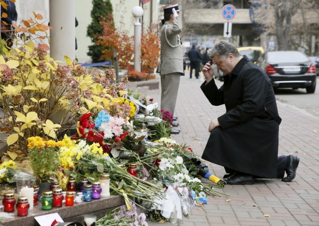 Ukraine's President Petro Poroshenko kneels near the French embassy as he commemorates victims of attacks in Paris, in Kiev, Ukraine, November 14, 2015. REUTERS/Valentyn Ogirenko